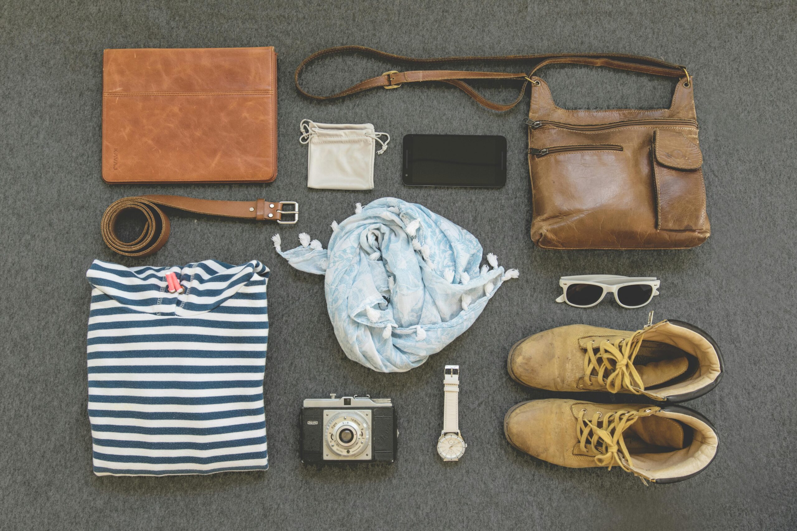 About Vintage travel essentials flat lay with leather bags, shoes, camera, and clothing.